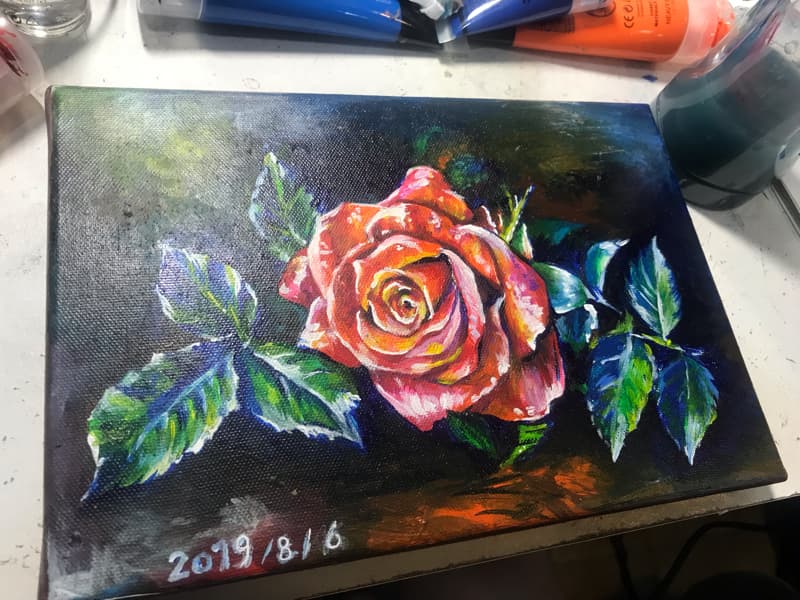 這張照片是一幅玫瑰花油畫，畫中有一朵鮮豔的紅色玫瑰，花瓣上有白色和粉紅色，襯託在深色背景上，顯得格外美麗。