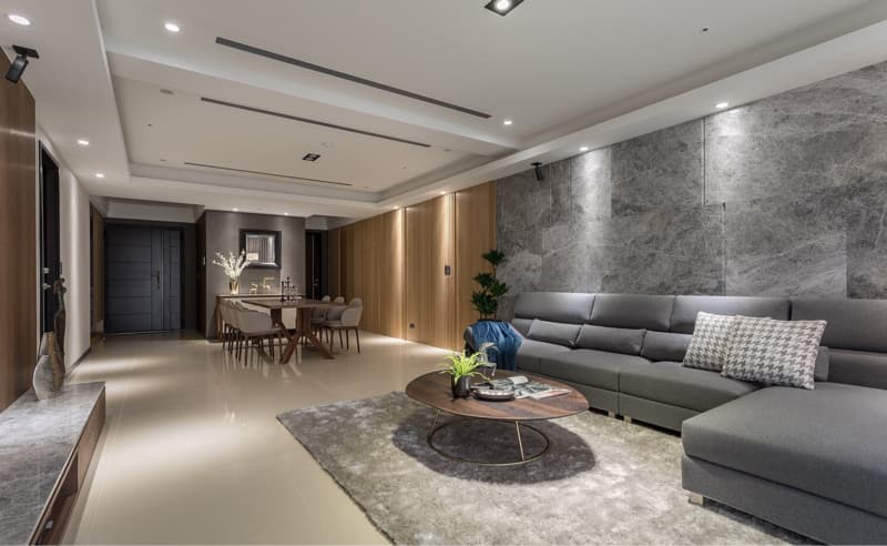 這張「客廳」的照片是一個現代化的空間，有著灰色石材牆面、灰色的沙發和一個圓形的咖啡桌。