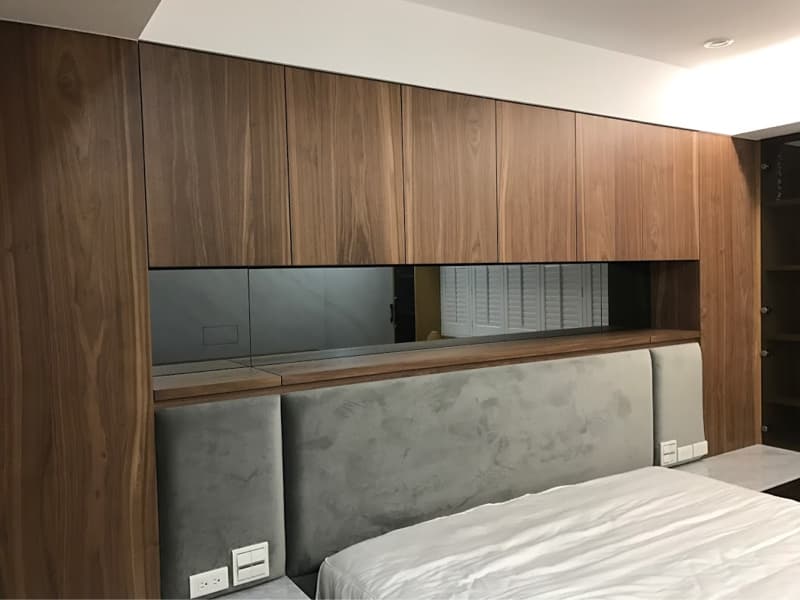 這張照片是臥室，照片中最主要的部分是床頭板，床頭板由兩片灰色的軟墊組成，上面有木頭的層架，層架上放著一個鏡子，鏡子反射著窗戶的景象。