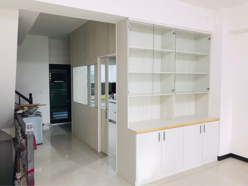 1) 照片顯示一個白色的櫥櫃，有玻璃門和抽屜，櫥櫃後面是透明的隔板，隔板的後面是一個房間，房間裡有門和一個櫃子