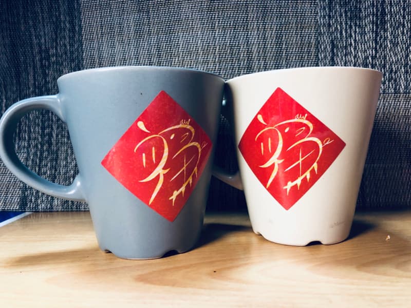 這張照片是兩個馬克杯，杯子上貼著紅色的福字貼紙。