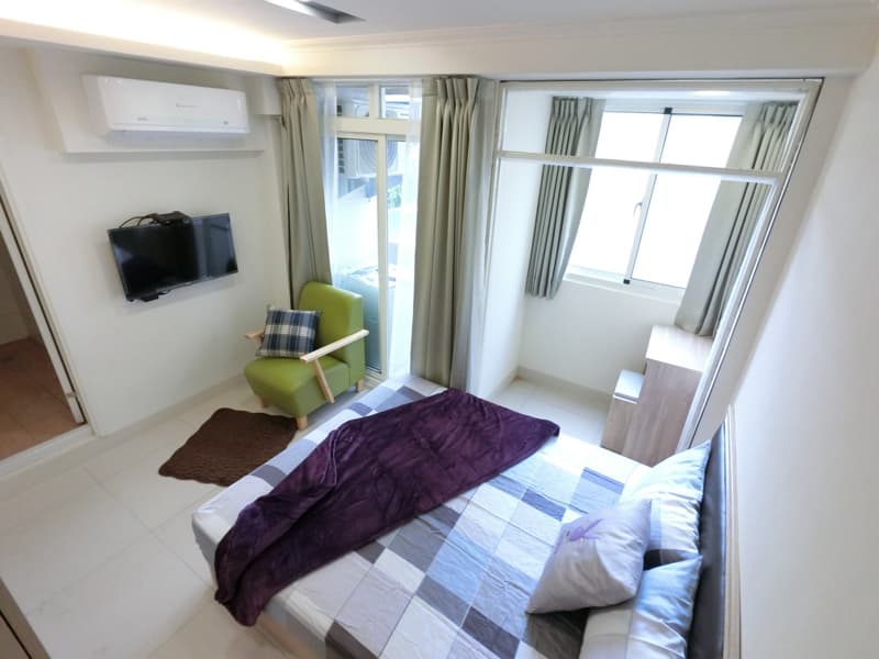 1) 照片顯示一間臥室，臥室裡有一張床、一個床頭櫃、一個沙發椅和一個電視