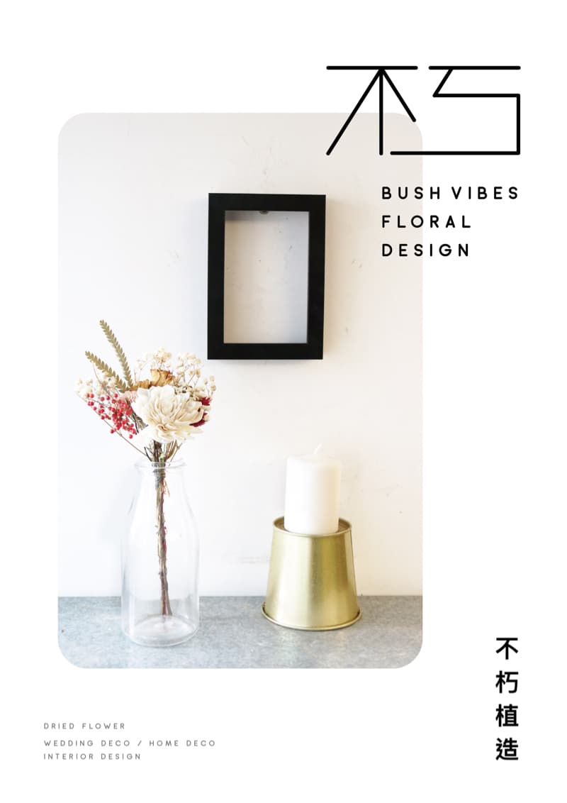 這張照片是一個裝飾著乾燥花的白色牆壁，牆上掛著一個黑色相框，下方擺放著一個金色的燭臺和一支白色的蠟燭。