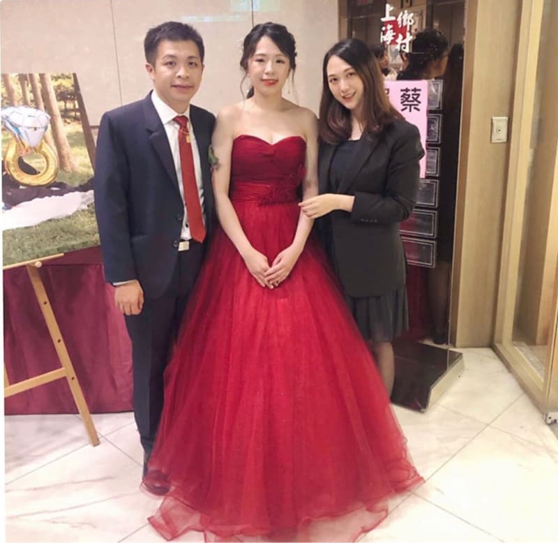 這張「婚禮」的照片是新郎穿著西裝，新娘穿著紅色禮服，旁邊站著一位女性友人。