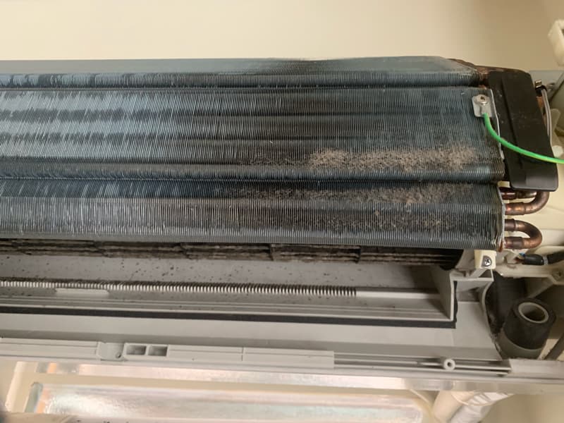 1) 照片顯示了一個髒污的空調冷凝器，覆蓋著灰塵和碎屑