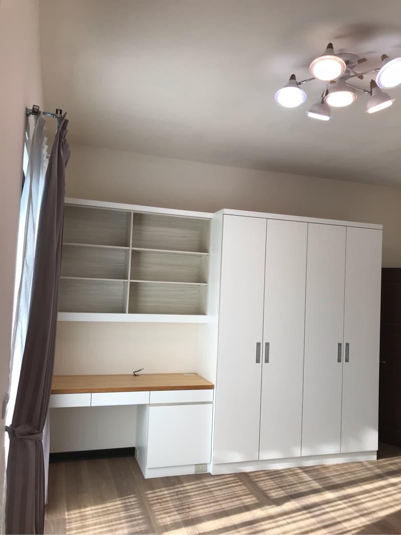 這張照片是一個簡約的書房，其中最重要的是一個白色書桌和一個白色書櫃。書桌上有木質桌面，方便閱讀或寫作，而書櫃則可以存放書籍和其他物品，保持書房的整潔和井然有序。