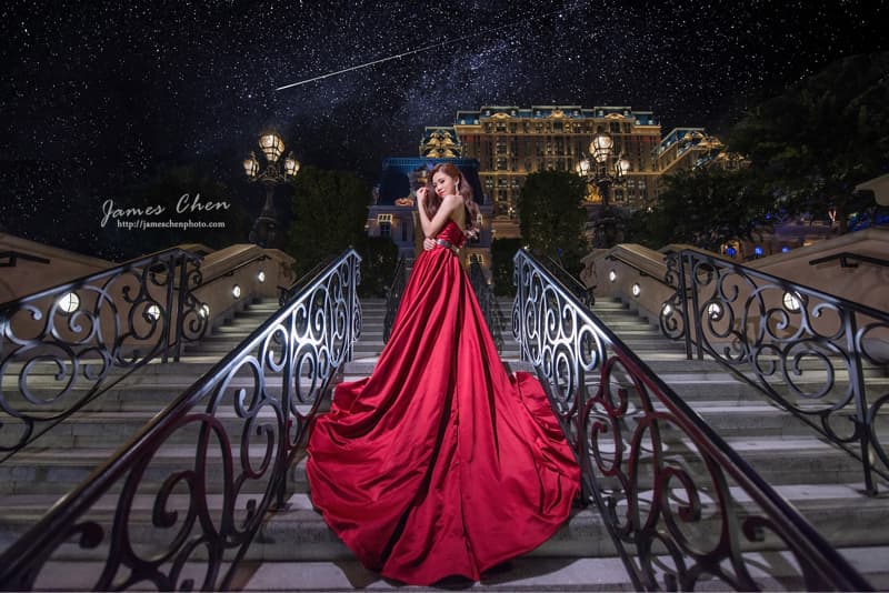 這張照片是一個穿著紅色禮服的女子站在階梯上，她美麗的禮服和閃爍的星空形成鮮明對比，呈現出浪漫唯美的氛圍。