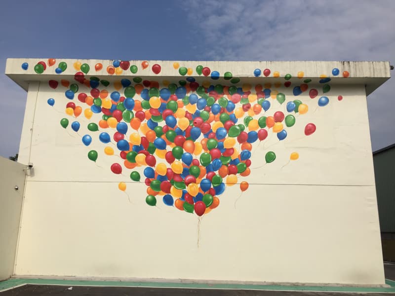 這張「牆壁上畫著許多五顏六色的氣球」的照片是，氣球飛向天空，象徵著希望與夢想。