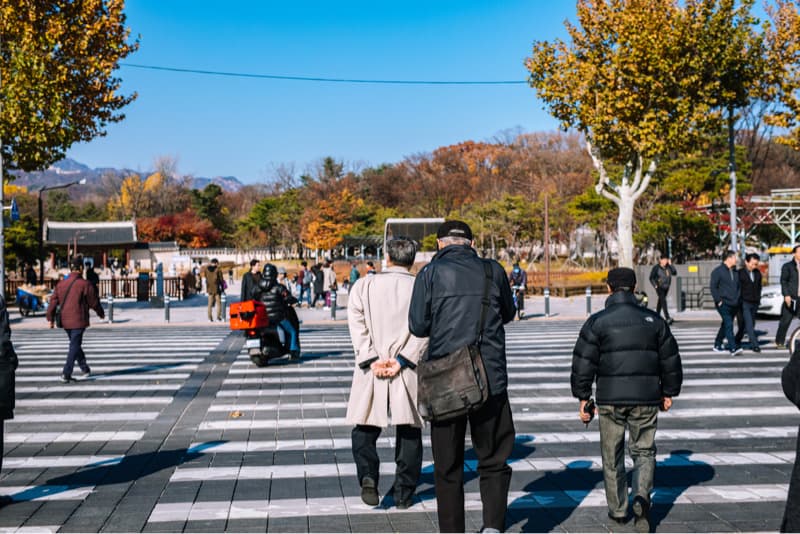 這張「街道」的照片是人們走在斑馬線上的景象，背景是一排樹木和建築物，讓人感受到寧靜和悠閒的氛圍。