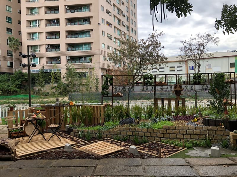 這張照片是一片由木板和石頭建造的小花園，裡面的桌椅和花草植物，讓人覺得很舒適放鬆。