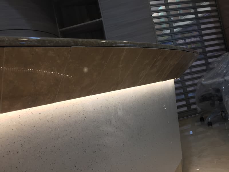 這張照片是一個帶有光線的櫃台，它上面是褐色的石頭，下面是白色的石頭，它們看起來很光滑。