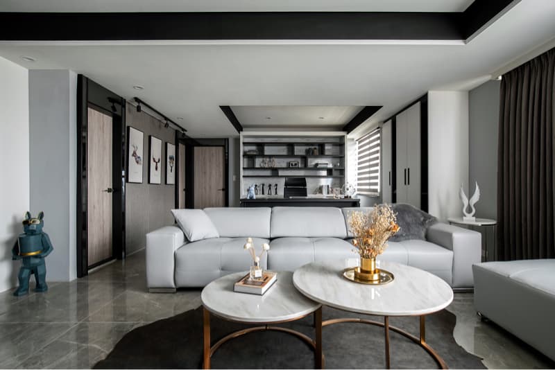 這張「客廳」的照片是一個現代化的空間，有著灰色的沙發，兩張圓形的茶几和一個白色的擺設。