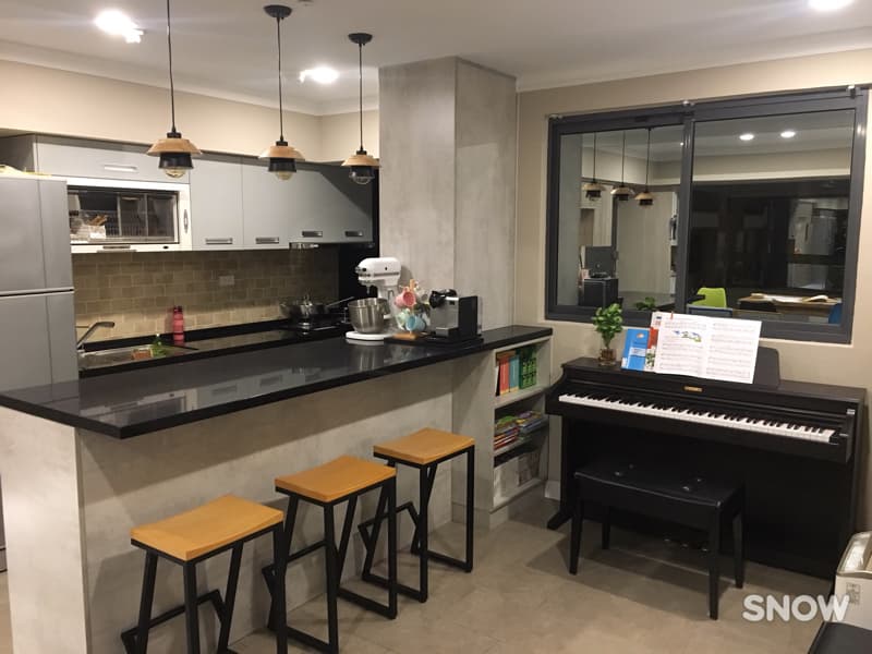 這張照片是現代化的廚房，其中最重要的部分是黑色的鋼琴，鋼琴上放著一本书和一張樂譜，看起來像是鋼琴演奏者的私人空間。