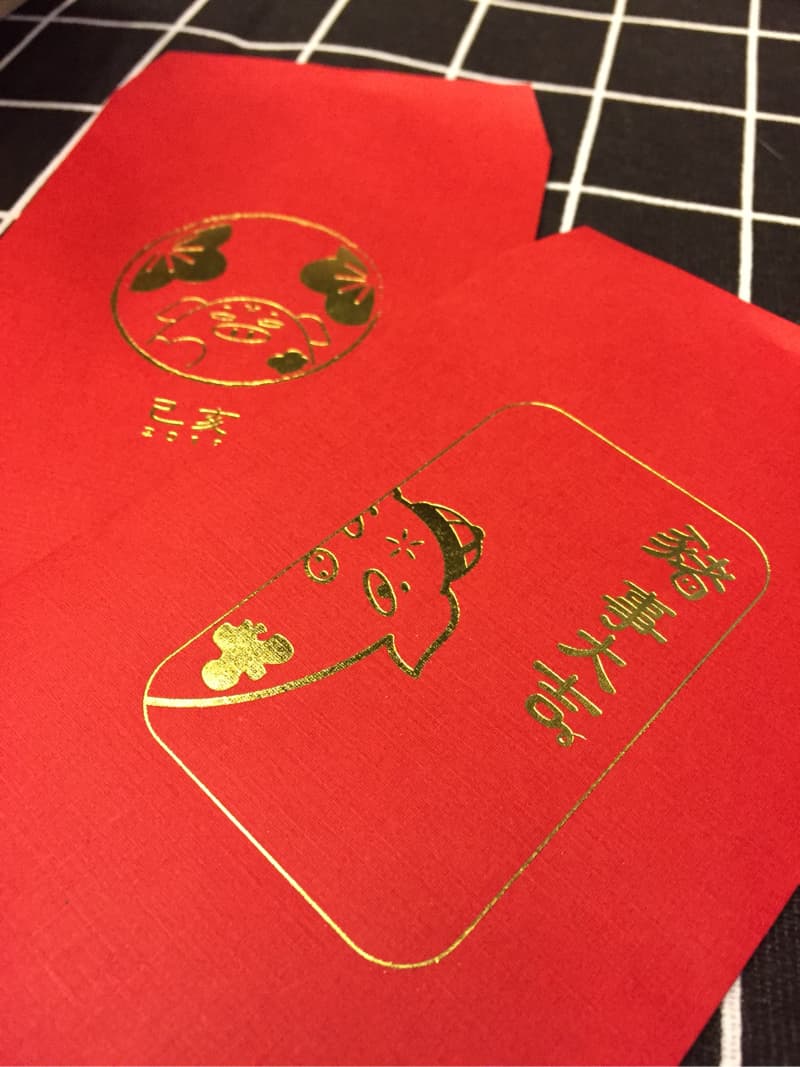 這張照片是一張紅色的利是封，上面印著金色的豬的圖案和“新年快樂”四個字，代表著新春的祝福。