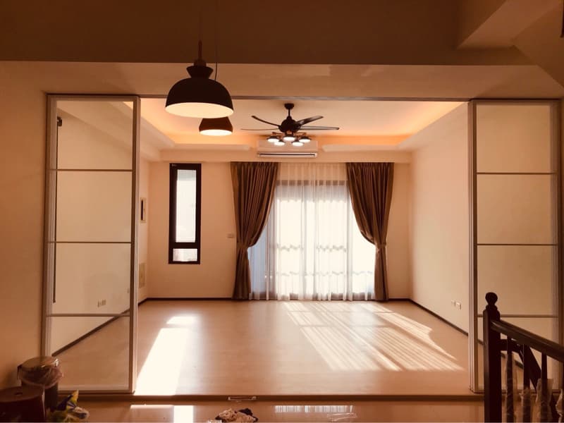 1) 照片顯示一個帶有落地窗的空曠客廳，客廳採用簡約的裝飾，配有木地板和白色天花板