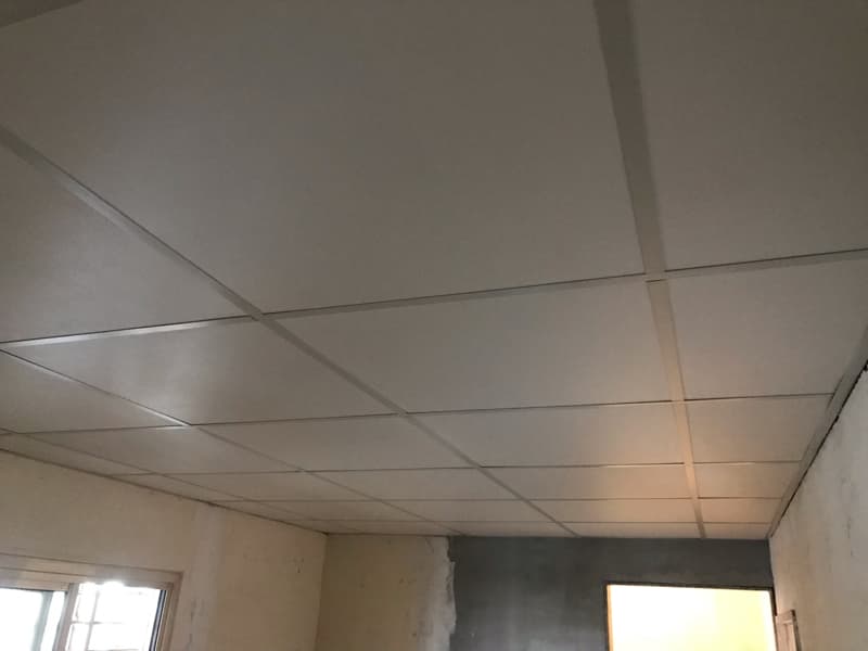 這張照片是房間裡安裝好的天花板，它由多個白色方形的吊頂板组成，板與板之間以灰色的線條接縫，形成網格狀。 
