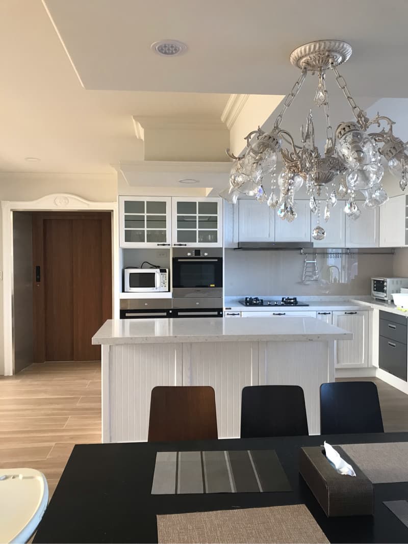 這張照片是一間現代化的廚房，其中最顯眼的是一個水晶吊燈，它懸掛在中間，散發著璀璨的光芒。