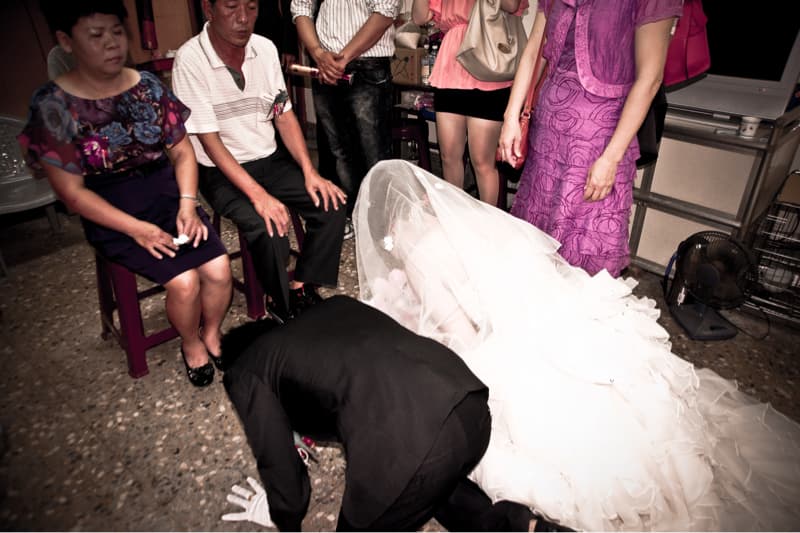 這張照片是一個婚禮的場景，照片中，一位身穿西裝的男士正跪在地上，向一位穿著白色婚紗的女士行禮。