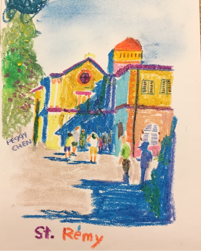 這張照片是一幅用蠟筆畫的風景畫，畫的是一間教堂，教堂旁還有幾棟房屋，屋頂上鋪著紅色的瓦片。