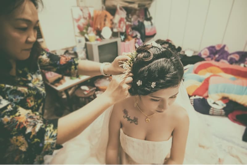 這張照片是一個新娘正在準備婚禮，她的伴娘正在幫她整理頭飾。