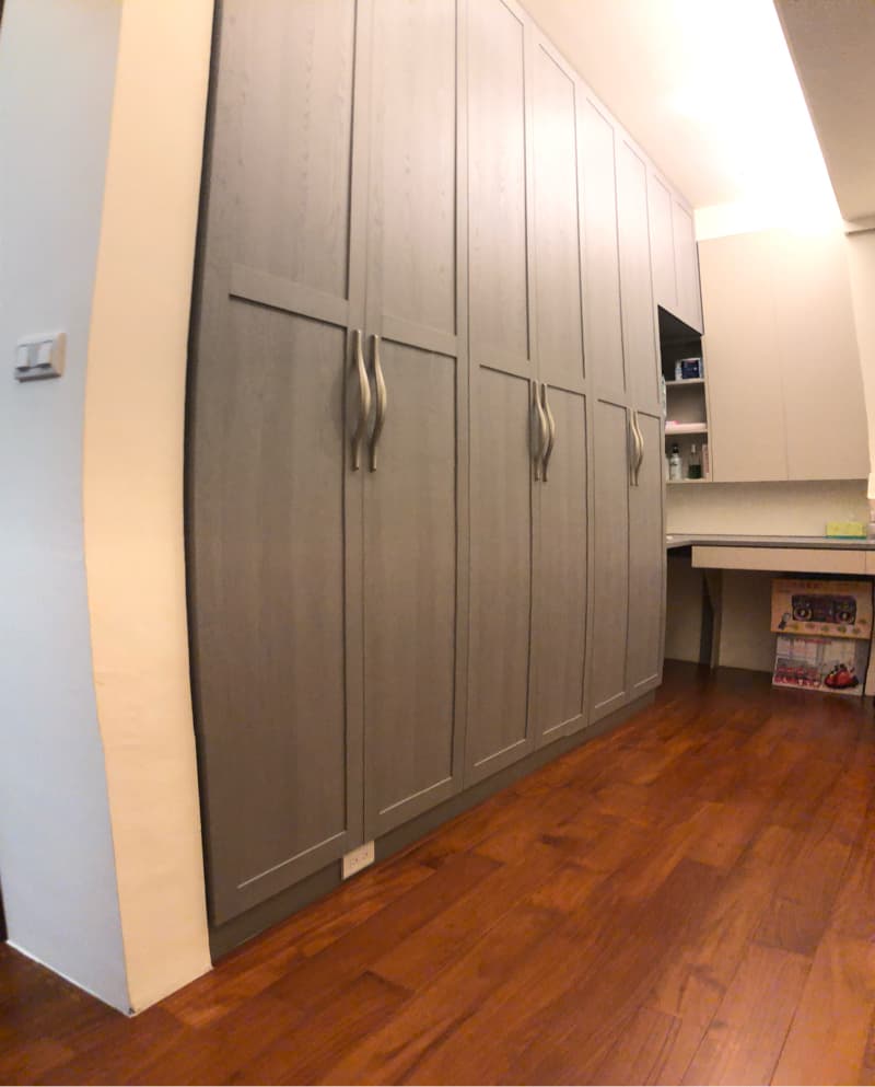 這張照片是一排灰色木紋櫃子，櫃門上裝飾著簡約的銀色把手，柜子下方是紅褐色的木地板，展現出簡約又大氣的風格。