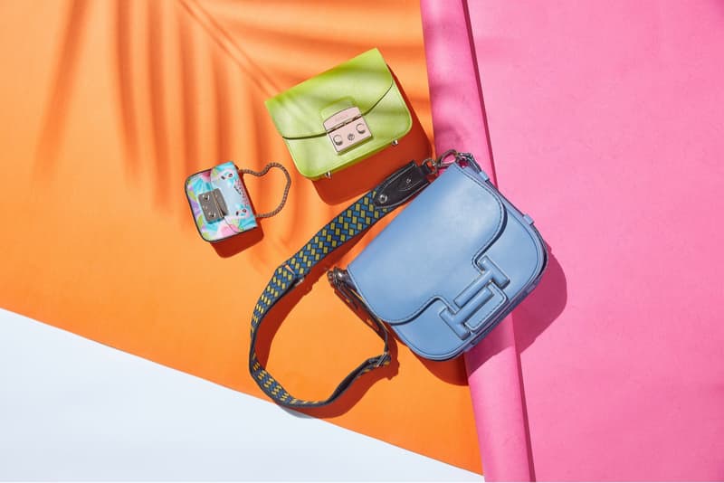 這張「三個包包」的照片是，一個綠色的包包，一個印花的包包，還有一個藍色的包包，它們放在橘色、粉色和白色的背景上。