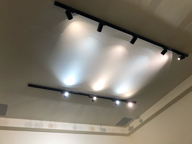 這張照片是天花板上的軌道燈，燈光照射在牆壁上，形成幾道柔和的光線。