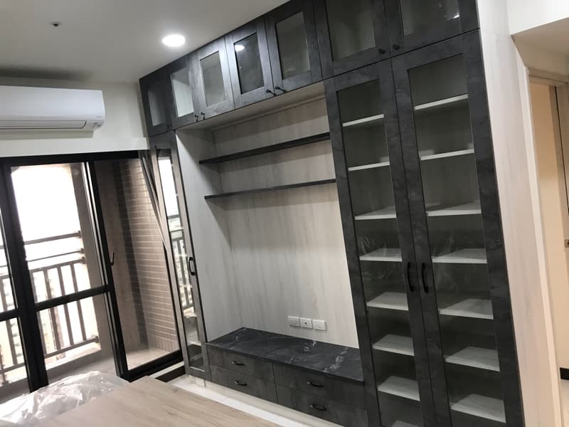 這張照片是客廳牆壁上的一個大型收納櫃，櫃子以灰色木紋為底，配上玻璃門，看起來簡潔大方，很有現代感。