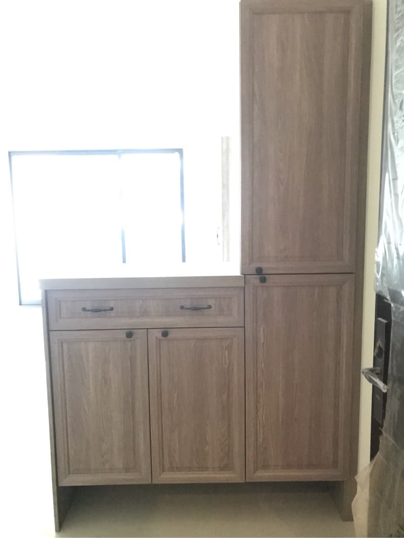 這張照片是一個木質櫥櫃，上面有一個抽屜和兩個櫃門，櫃門上配有黑色把手。