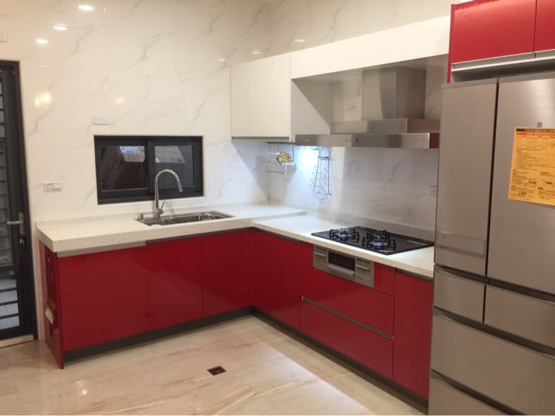 這張照片是一間廚房，最顯眼的部分是紅色的櫥櫃和白色的流理台。
