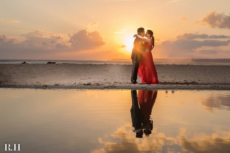 這張照片是一對情侶在海邊的夕陽下擁吻，他們的背影被夕陽的光線照耀，在他們身後的沙灘上留下長長的影子。