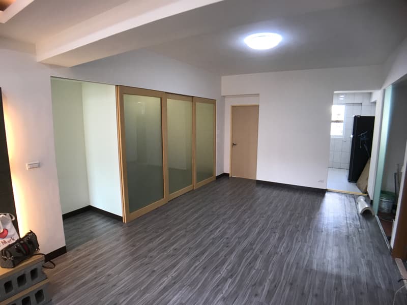 1) 照片顯示一個空房間，房間有木地板，牆壁是白色的