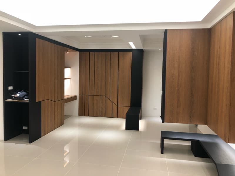 這張照片是一間裝潢精緻的現代化室內空間，以木質色系為主，並搭配黑色線條，營造出簡約大方的視覺效果。左側牆面上的木質櫃子，設計成開放式的層架，讓空間更顯通透。櫃子上的黑色邊框，則增添了幾分現代感。