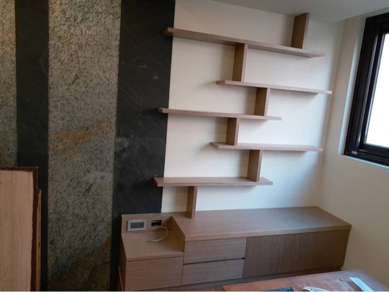 這張照片是牆上的一個木製書架，書架由多個層板組成，並以不規則的形狀排列，整體設計簡潔且現代。