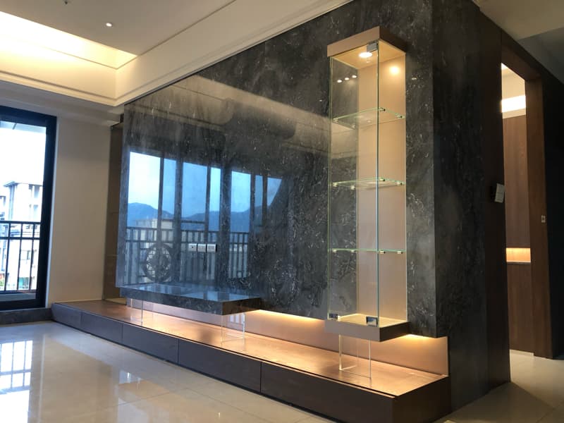 這張照片是一個現代化的客廳，牆上裝飾着一個玻璃展示櫃，櫃子裡有燈光照射，讓玻璃櫃更加明亮，看起來很美觀。