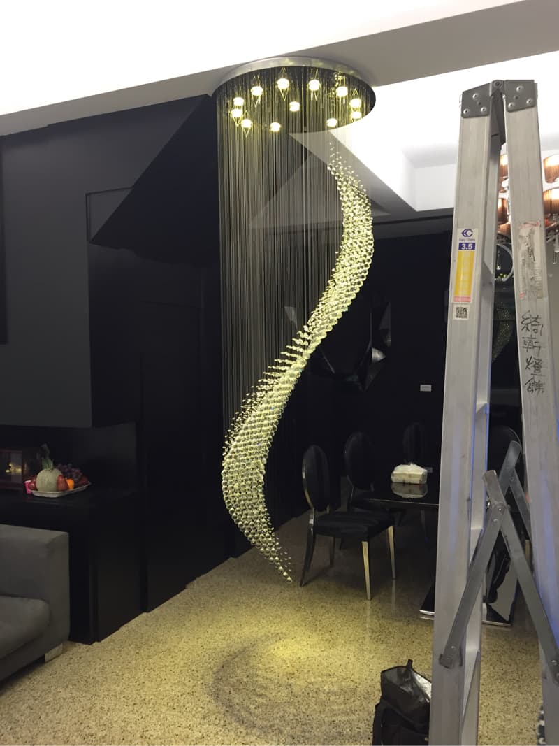 1) 照片中顯示的是一間現代室內設計的房間，房間的中央掛著一個大型水晶燈，水晶燈的造型為螺旋狀，燈光照亮了整個房間