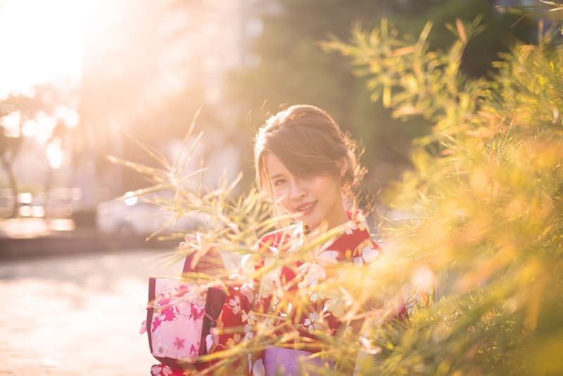 這張照片是一個穿著和服的年輕女子站在陽光灑落的草叢中。