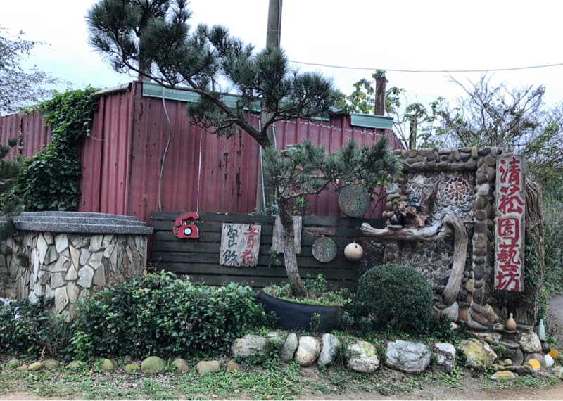 這張照片是一間用石頭堆砌的門面，上面掛著一個紅色招牌，寫著「清涼園藝」。