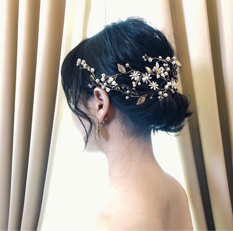 這張「新娘」的照片是一名穿著白色禮服，頭戴著花朵髮飾的新娘，她站在窗戶前，背對著鏡頭，背景是白色窗簾。