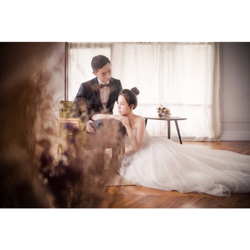 這張「婚紗照」的照片是一對新人在室內拍攝，新娘穿著白色婚紗，新郎穿著黑色西裝，他們看起來很幸福。