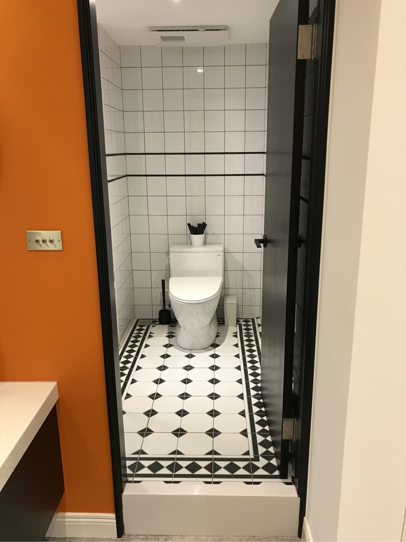 這張照片是一個浴室，最顯眼的部分是黑白相間的瓷磚地板，中間是一塊凸起的白色瓷磚，讓地板看起來更加具有層次感。 
