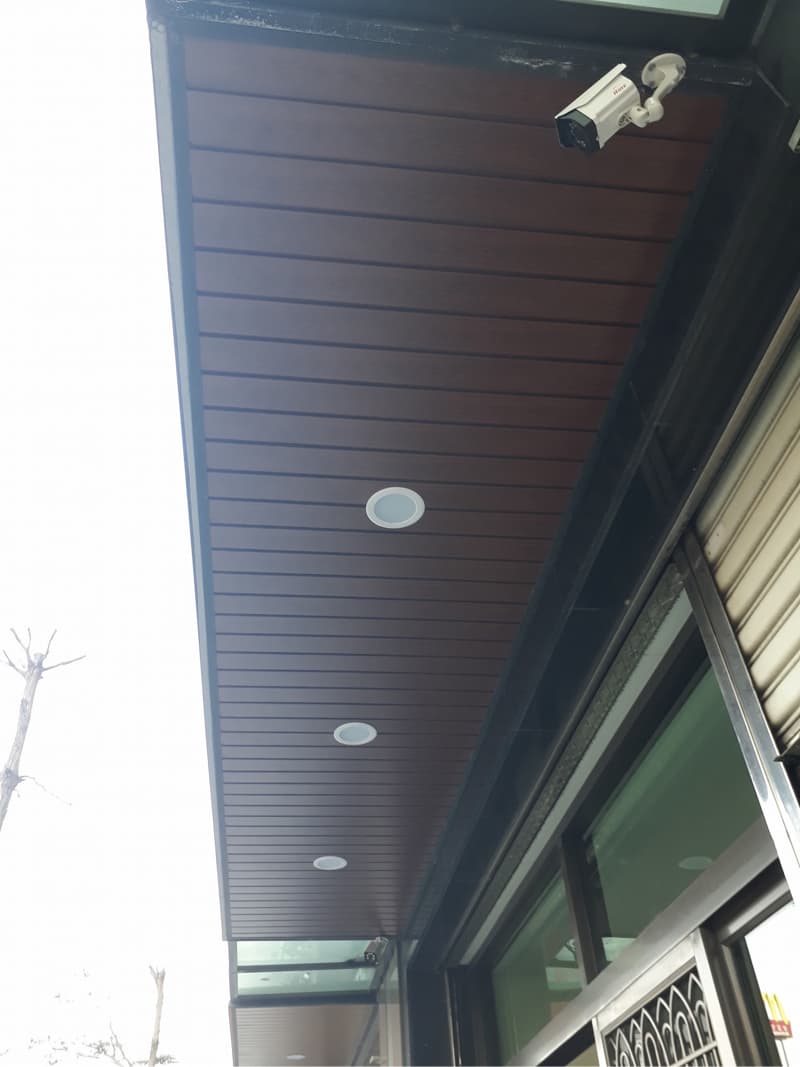 1) 照片展示一個建築物的屋頂，屋頂上有木紋的裝飾板，還有三個圓形的燈以及一個監視器