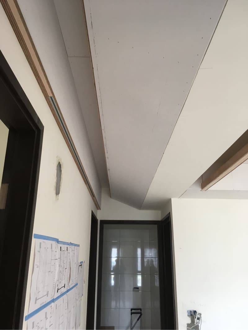 這張照片是正在裝修的房子的天花板，天花板設計採用了多層次的設計，並在邊緣加入了木條，顯得精緻而有層次。