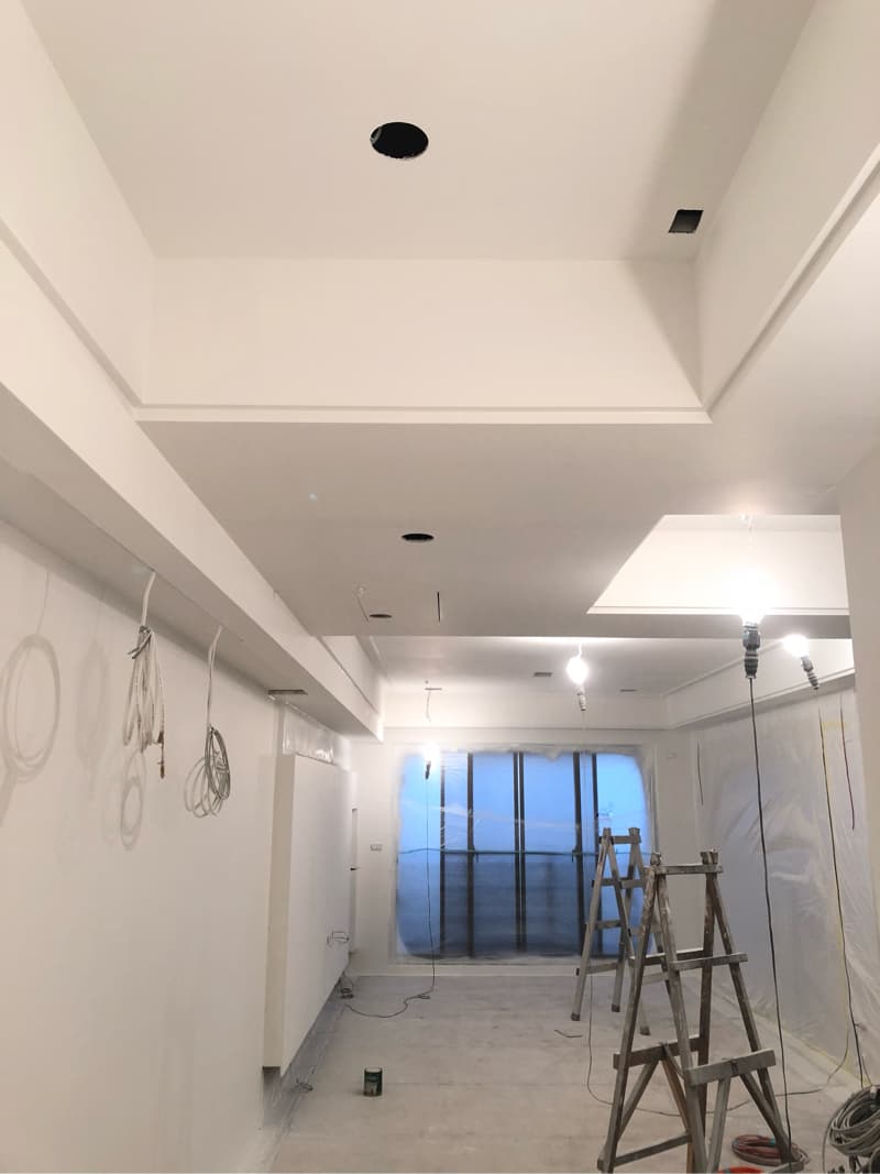 這張照片是一個正在裝修的房間，最顯眼的是天花板的設計，採用多層次的設計，讓空間更有層次感，並在每個層次上都設置了燈光，這也顯示出這個房間將會非常明亮。