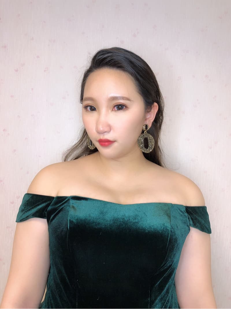 這張「女子穿著綠色天鵝絨禮服」的照片是，她看起來很優雅，戴著金色的耳環。