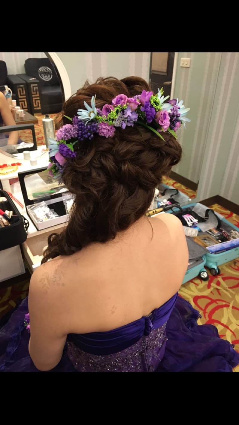 這張照片是一名女子，她戴著一個由紫羅蘭、粉紅色和藍色花朵組成的花環。