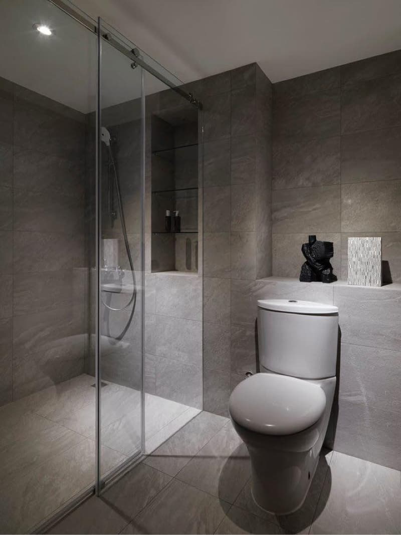 1) 照片顯示一個現代浴室，配有灰色瓷磚地板和牆壁，一個淋浴間，一個馬桶，一個洗手台以及一個置物架