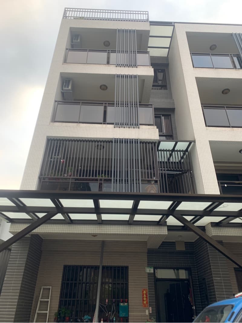 1) 照片顯示一座三層樓的建築物，外觀為白色牆面，搭配黑色窗框和欄杆