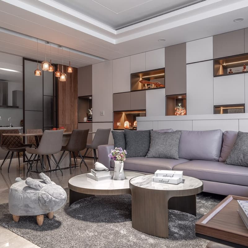 這張「現代風格的客廳」的照片是，展示了一個舒適的沙發、兩個咖啡桌和一個毛絨凳子，牆壁上裝飾著開放式的置物架。