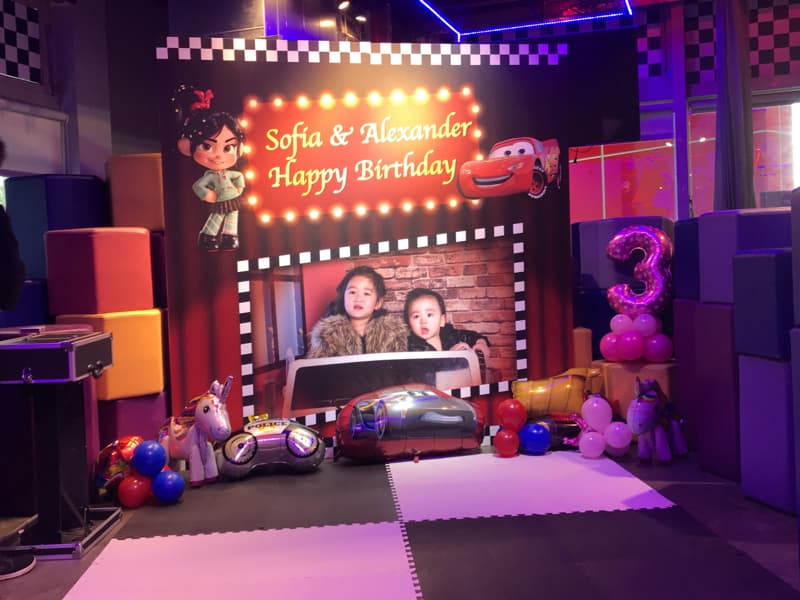 這張照片是一個兒童派對，最重要的是照片背景，上面有 "Sofia & Alexander Happy Birthday" 的字樣。